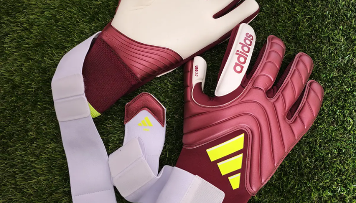 Luva de Goleiro Adidas Copa Pro Energy Citrus nas cores marrom, creme e verde fluorescente. Apresenta design com corte negativo para ajuste firme nos dedos, alça de pulso em elastano para personalização, dorso em mesh e látex para conforto e ventilação, além de palma com URG 2.0